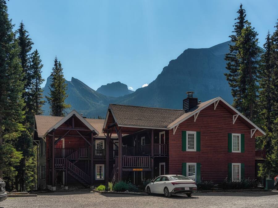 A rustic log cabin with a porch and a car parked in front.