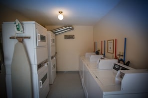 A laundry room with stacked washers and dryers, a drying rack, and a sign indicating the room's purpose. - Paradise Lodge & Bungalows (Lake Louise)