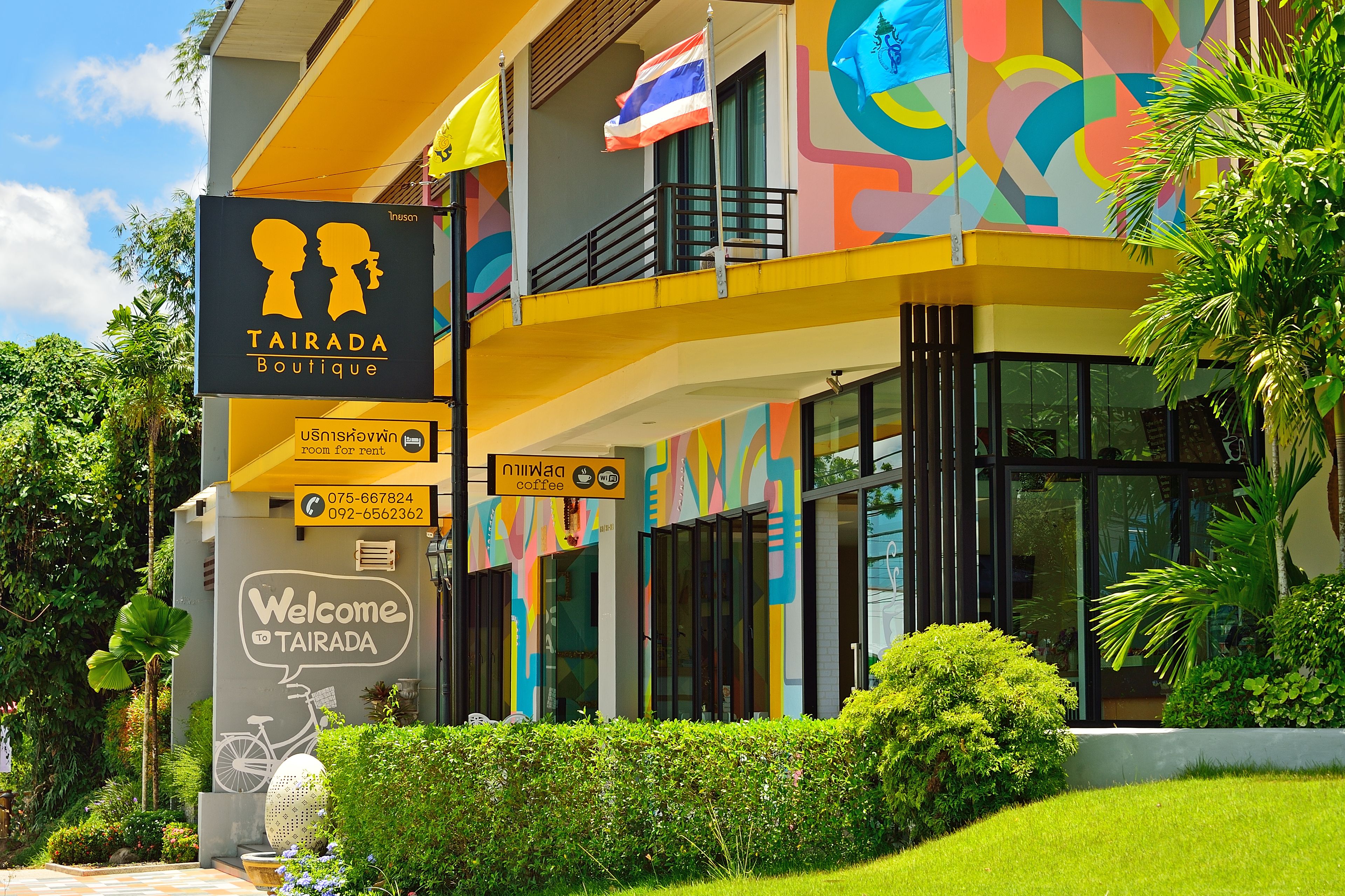 A colorful building with a sign for Tairada Boutique, a coffee shop, and a welcoming sign.