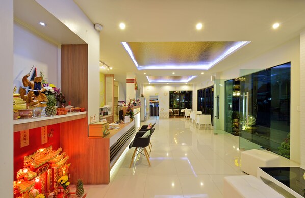 Un moderno vestíbulo de hotel con mostrador de recepción, zona de estar y escaparate de vidrio.