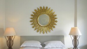 Una habitación de hotel con una cama, dos lámparas de noche y un espejo con diseño de sol en la pared.