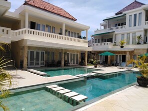A hotel with a swimming pool, outdoor seating, and multiple balconies. - Bali Court Hotel and Apartments (Legian)