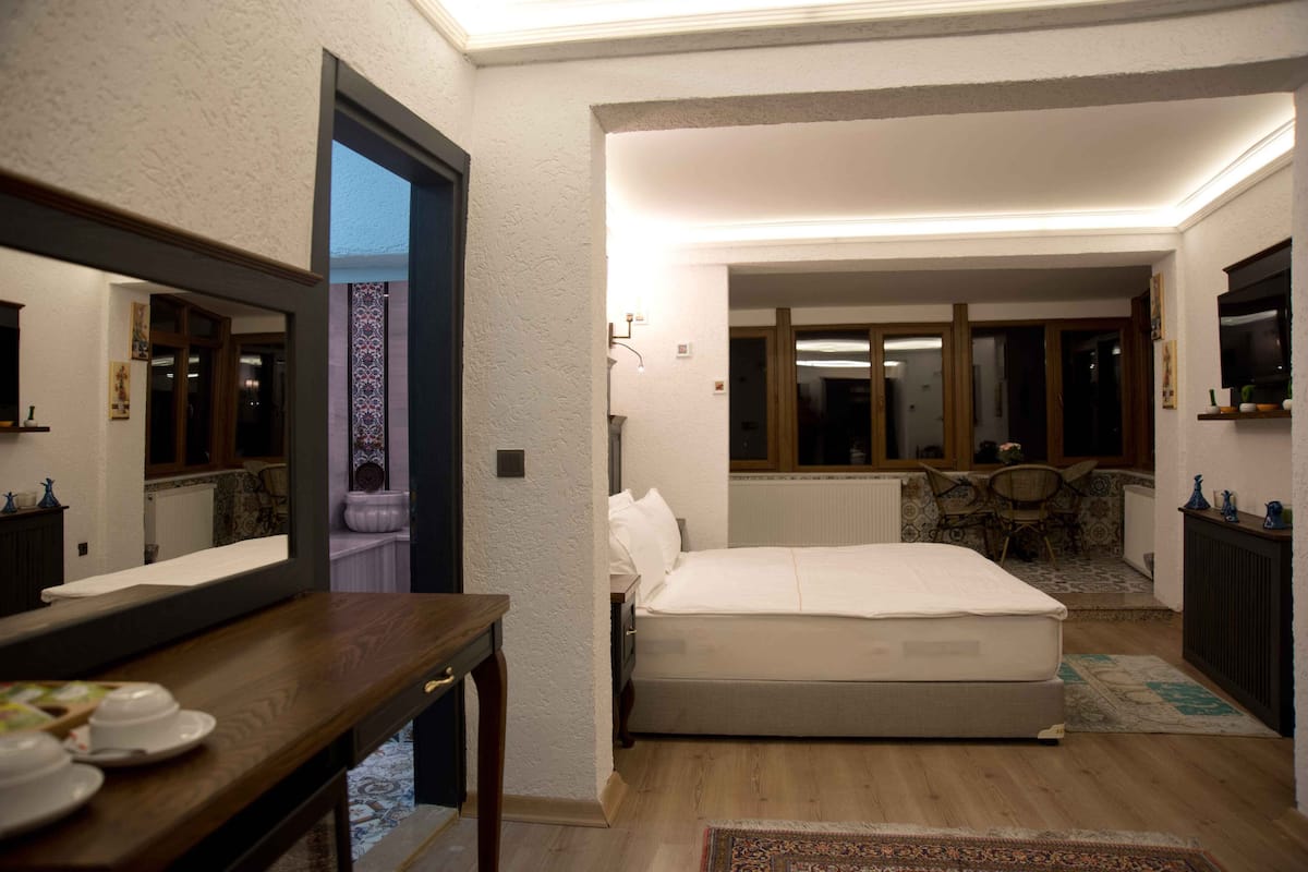 A bedroom with a bed, a dresser, a mirror, and a window.