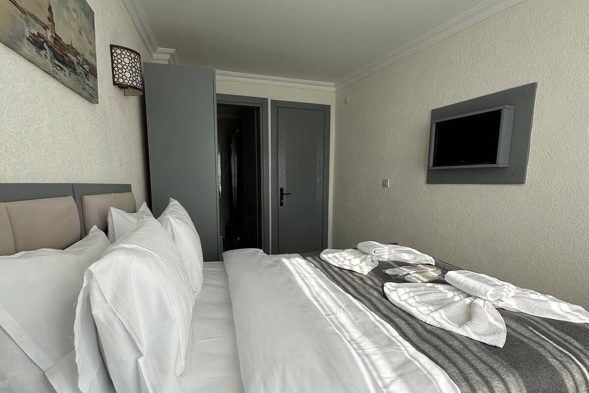 A hotel room with a bed, a TV, and a door leading to a hallway.