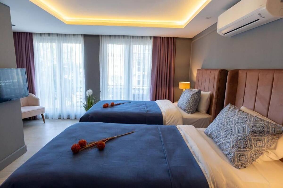 Habitación de hotel con dos camas, televisión, escritorio y ventana con cortinas.