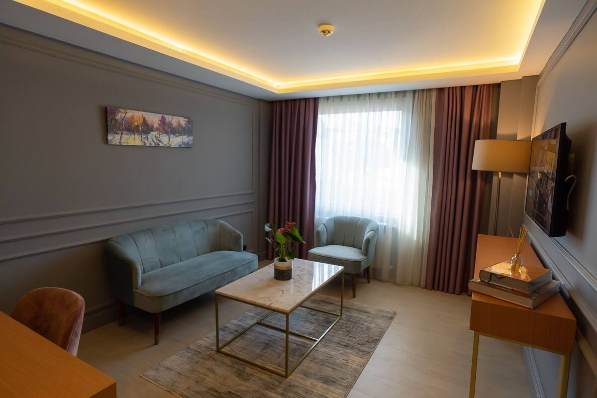 Una sala de estar moderna con sofá, sillón, mesa de centro y televisor sobre un mueble.