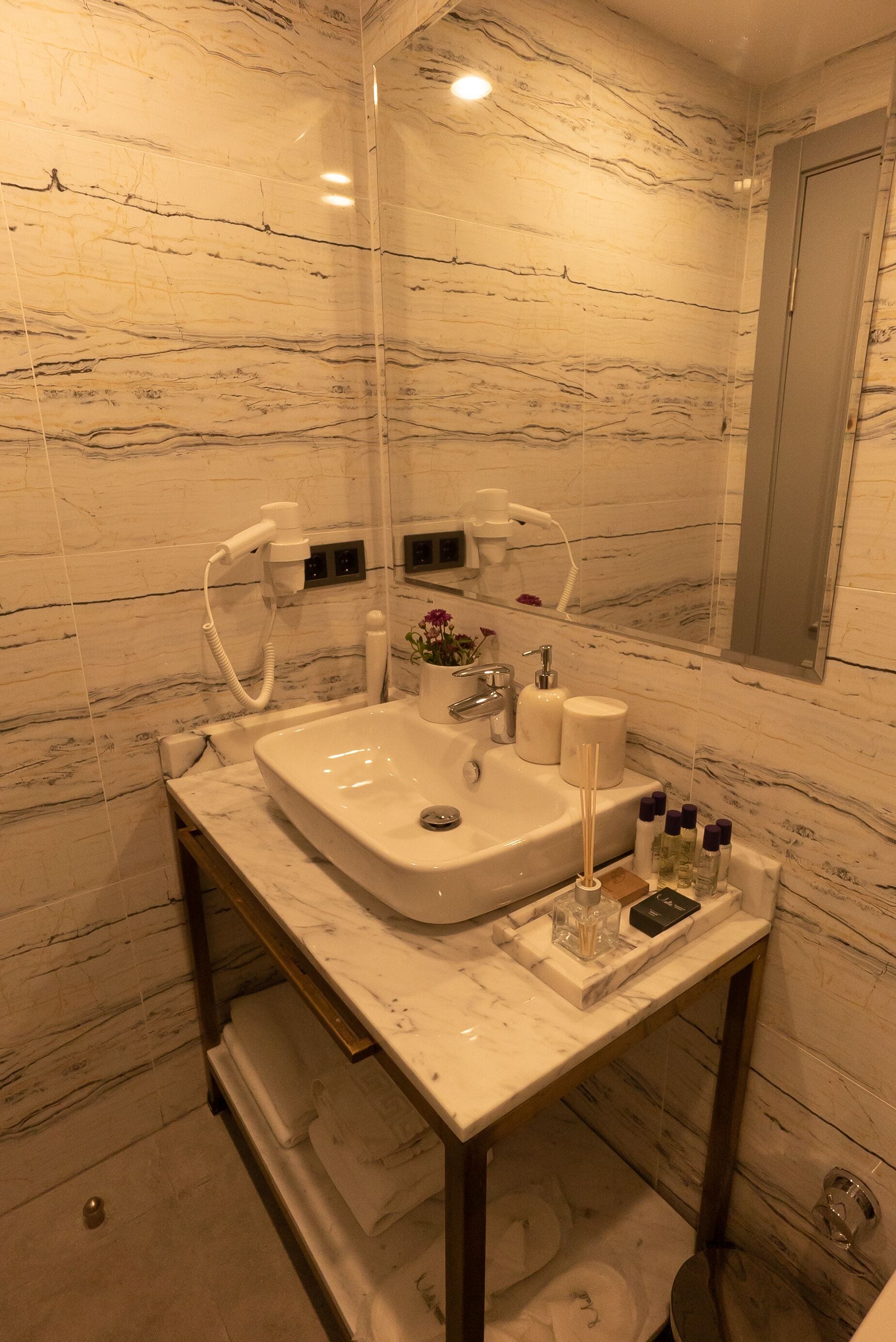 A bathroom with a marble sink, a mirror, a towel rack, and a toilet.