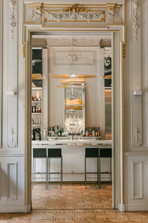 A bar area with a mirror, stools, and shelves of bottles. - C2 hôtel (Marseille)