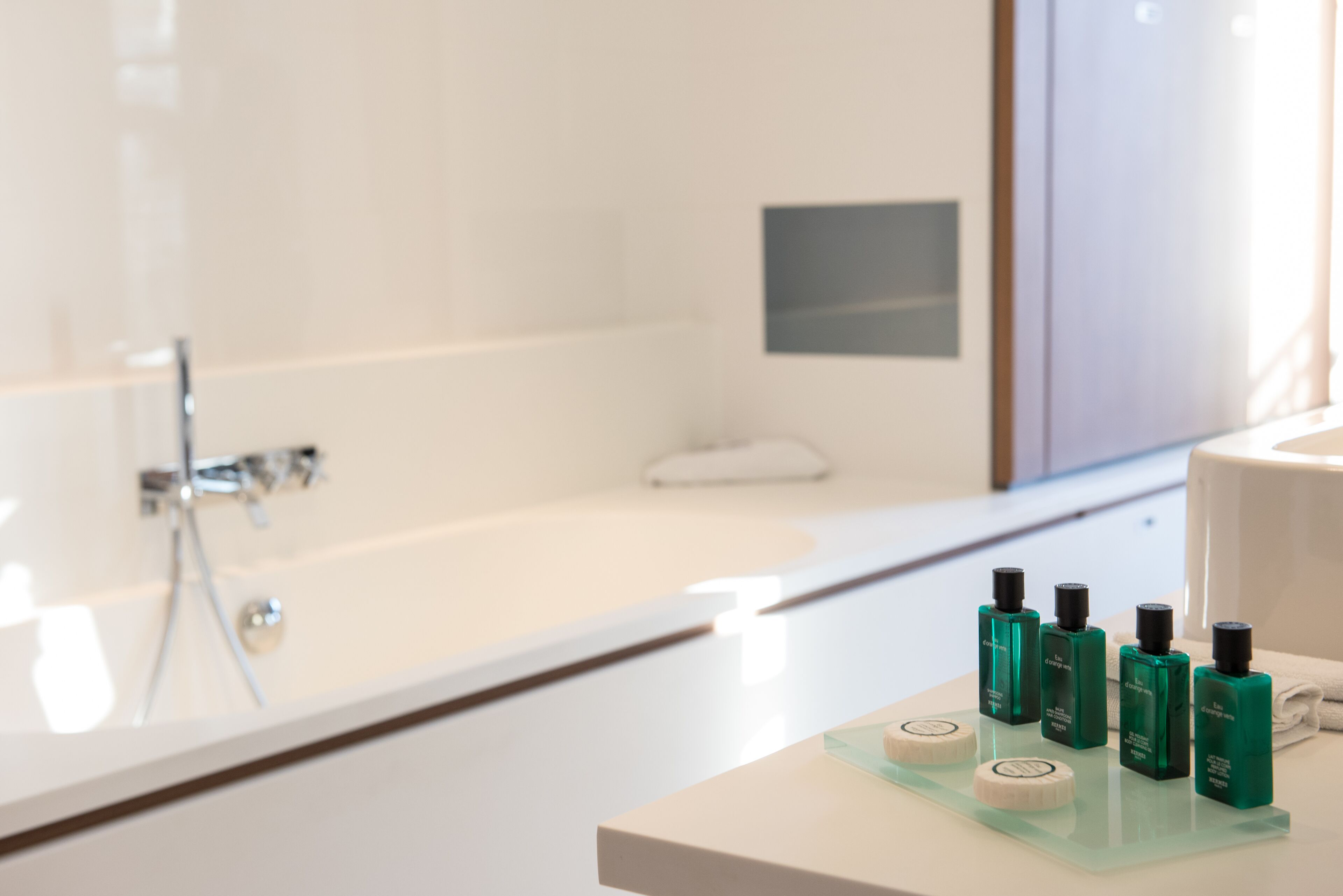 Une salle de bain moderne avec une baignoire blanche, une douche en verre et un meuble-lavabo agrémenté de produits de soins pour la peau.