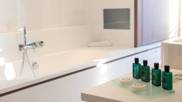 Une salle de bain moderne avec une baignoire blanche, une douche en verre et un meuble-lavabo agrémenté de produits de soins pour la peau.