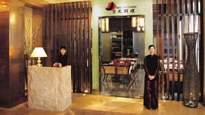Zona de recepción con mostrador, un jarrón grande y letrero de Cocina Japonesa.