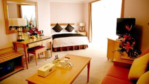 Una habitación de hotel con cama, escritorio, televisión y mesa de centro.