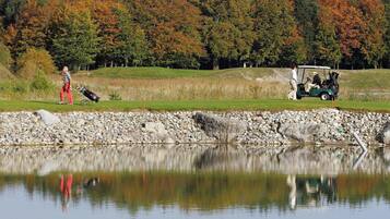 En golfbane med et spejlbassin, træer og en golfvogn.