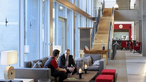 Een modern interieur met een trap, zithoeken en grote ramen.