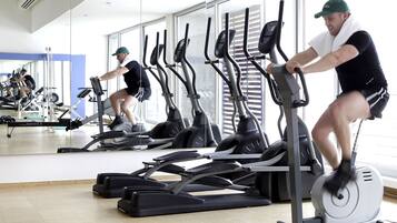 A gym with multiple stationary bikes and mirrors on the walls.