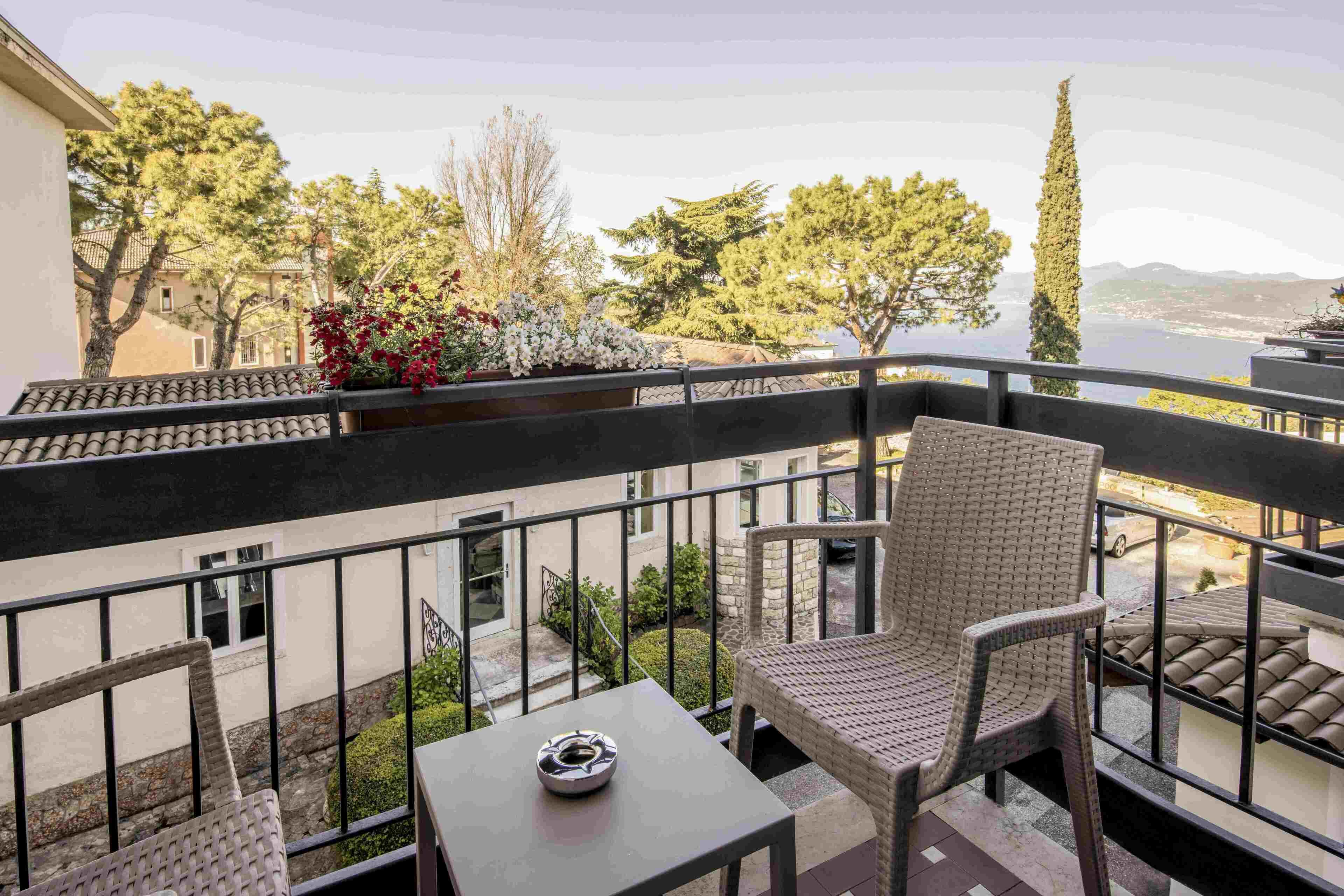 A balcony with wicker furniture, a table, and a view of trees and a body of water.