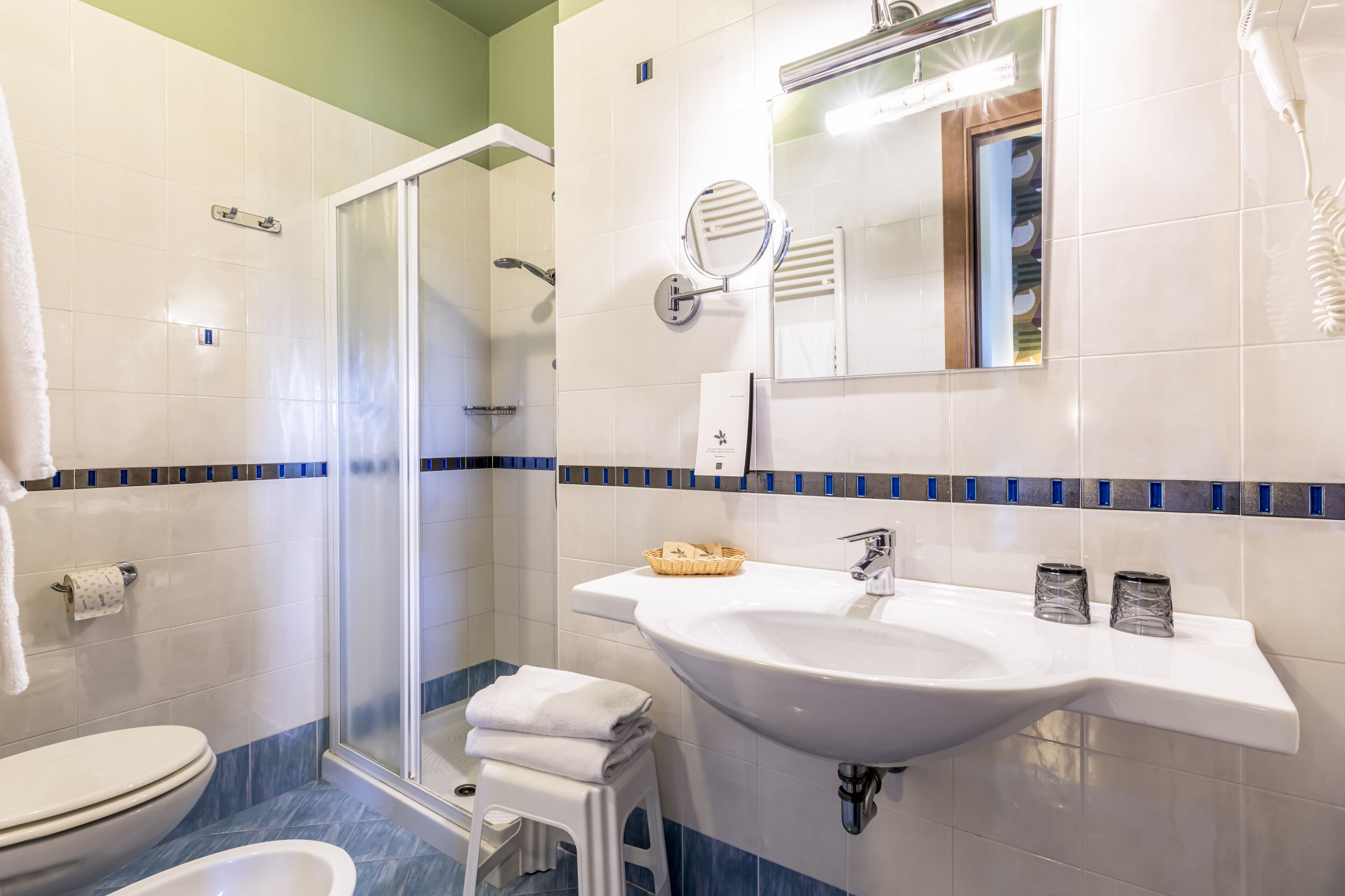 Une salle de bain avec un lavabo blanc, un miroir et une douche.
