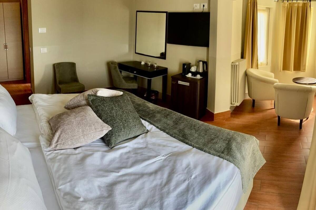 A hotel room with a bed, a desk, a chair, and a mirror.