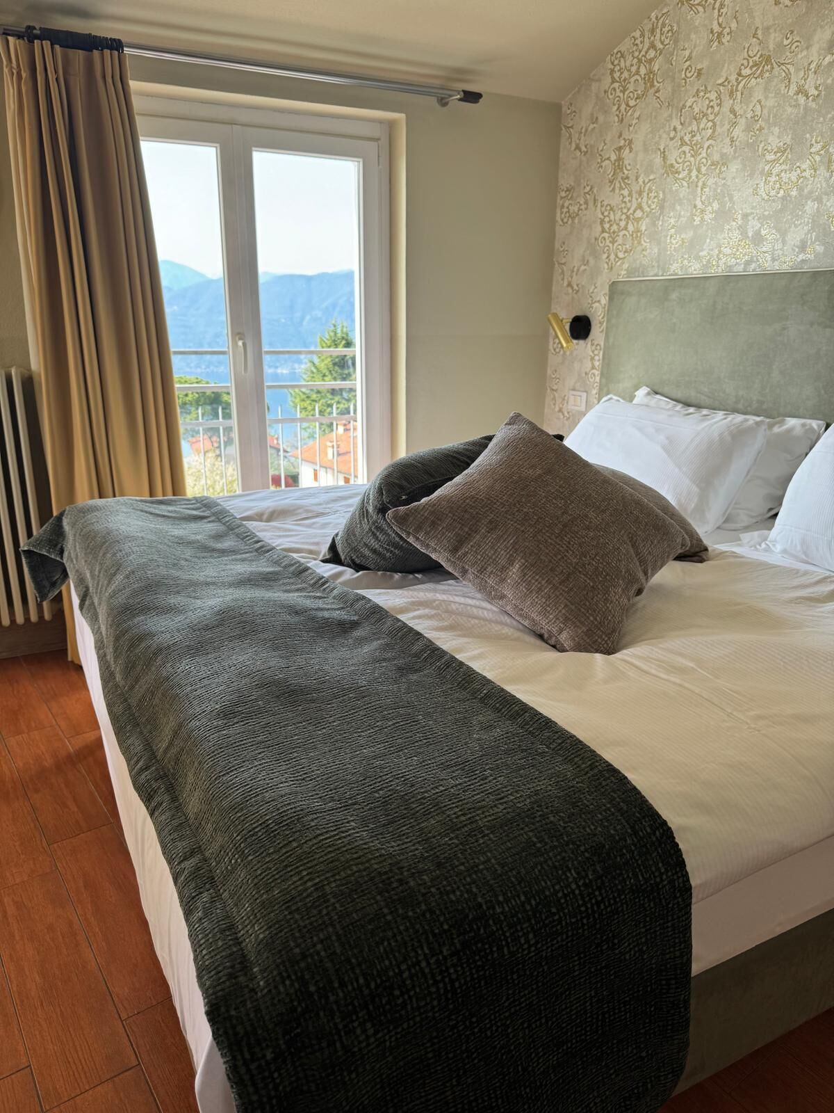 Una habitación de hotel con cama, vistas a montañas a través de una ventana y un radiador.