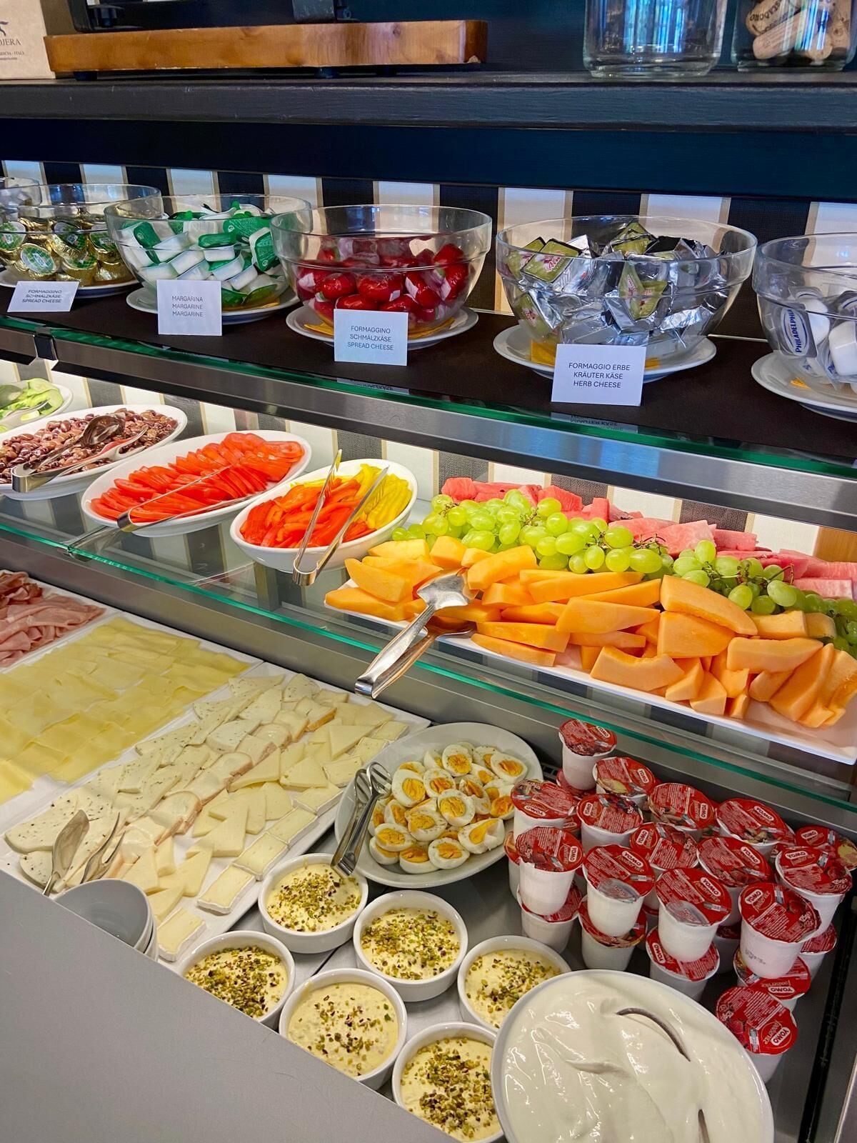 Ein Buffet mit verschiedenen Speisen, darunter Käse, Obst und Aufstriche.