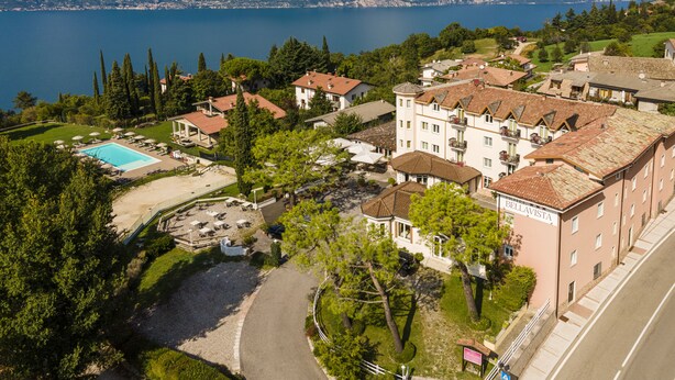 Un resort con piscina, varias construcciones y vistas a un lago y montañas.