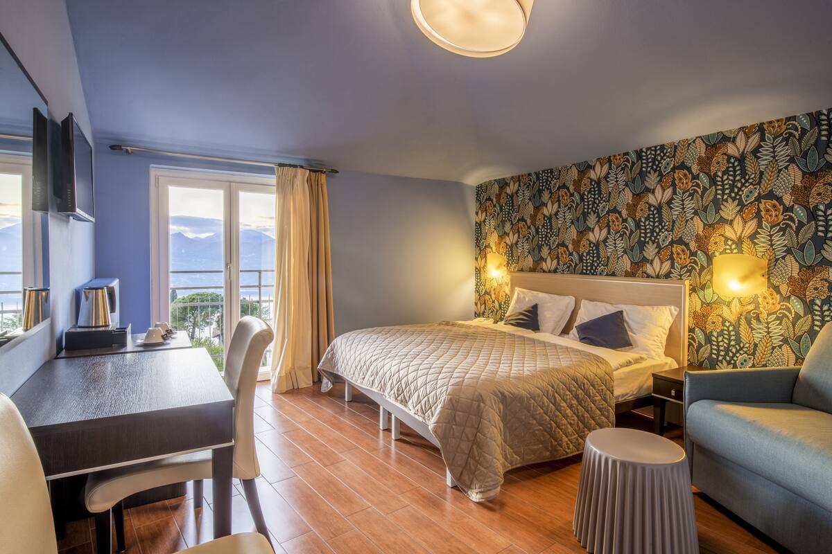 A bedroom with a bed, a desk, a chair, and a sofa.