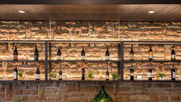 A bar area with shelves of wine bottles against a stone wall backdrop.