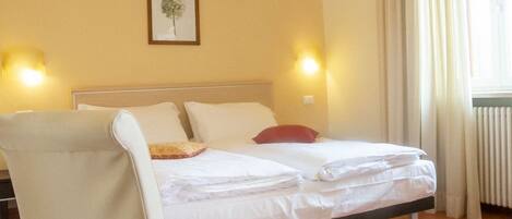A hotel room with a bed, a chair, a picture on the wall, and two wall-mounted lamps.
