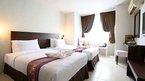 Habitación de hotel con dos camas, un escritorio, una silla, una mesita de noche y un aire acondicionado.