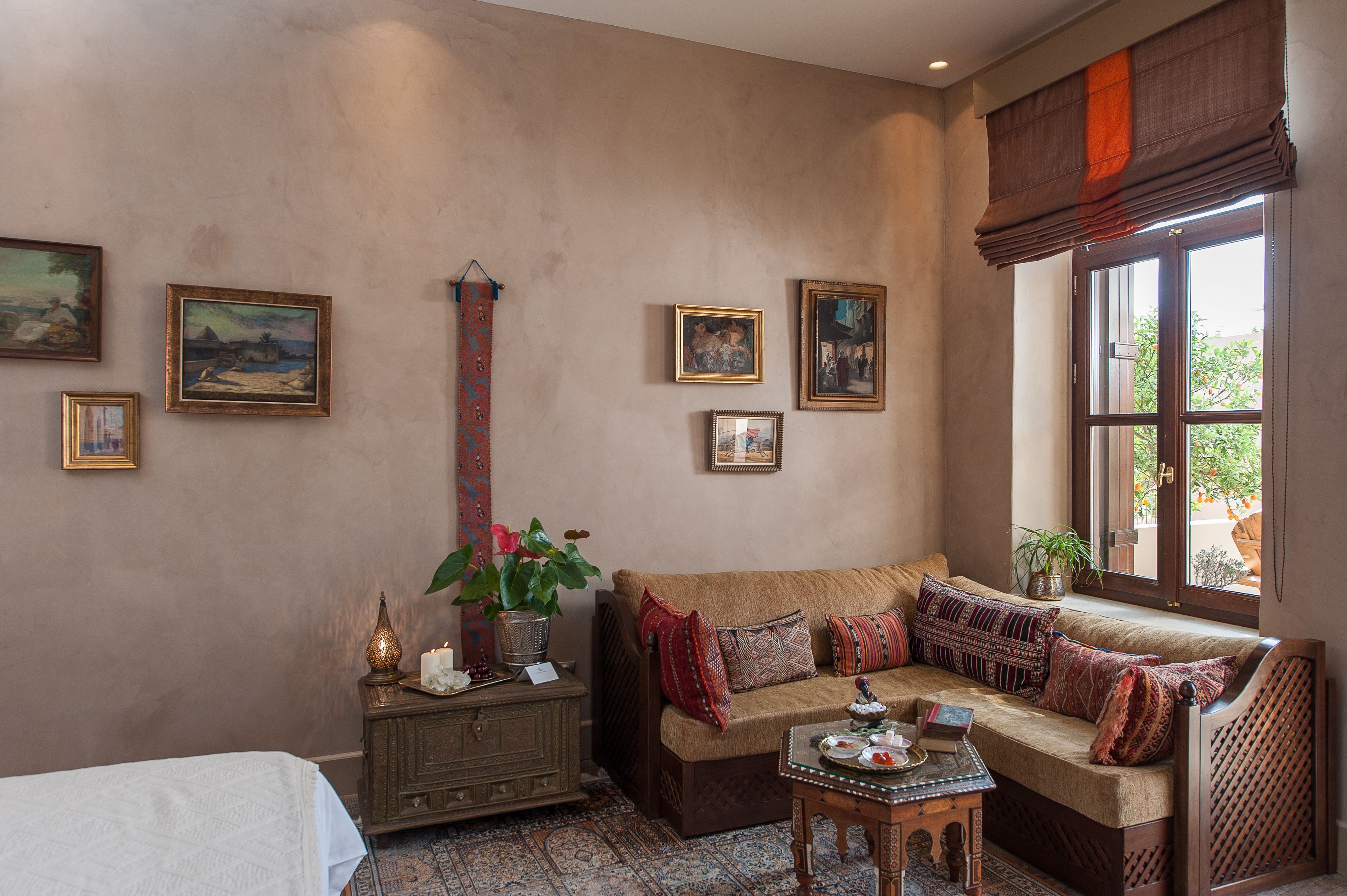 A cozy room with a sofa, a small table, and a cabinet. There are several framed pictures on the wall.