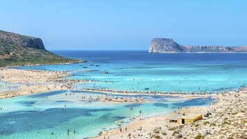 Una spiaggia costiera con acque cristalline, spiagge sabbiose e scogliere rocciose.