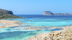 A coastal beach with clear waters, sandy shores, and rocky cliffs. - La Maison Ottomane (Chania)