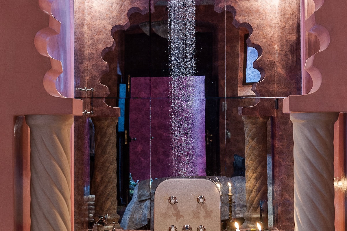 A luxurious bathroom with a large mirror, a chandelier, and a bathtub.