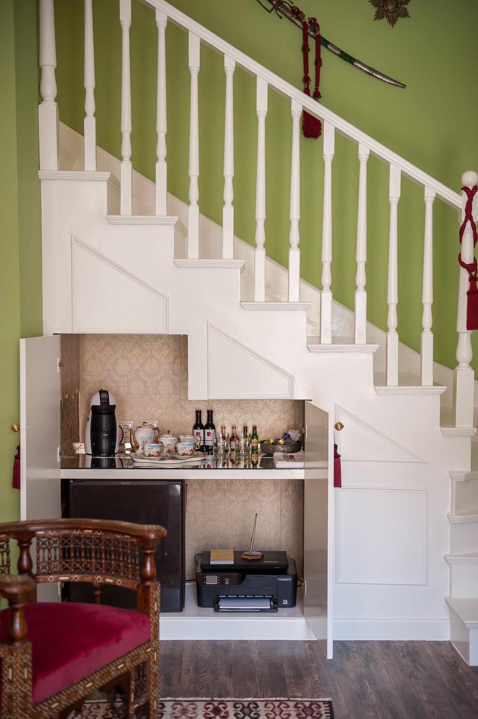 Una escalera con balaustres blancos y una pared verde.