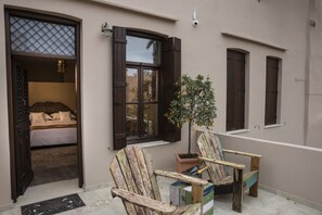 A room with a bed, a window with shutters, a potted plant, and two wooden chairs. - La Maison Ottomane (Chania)