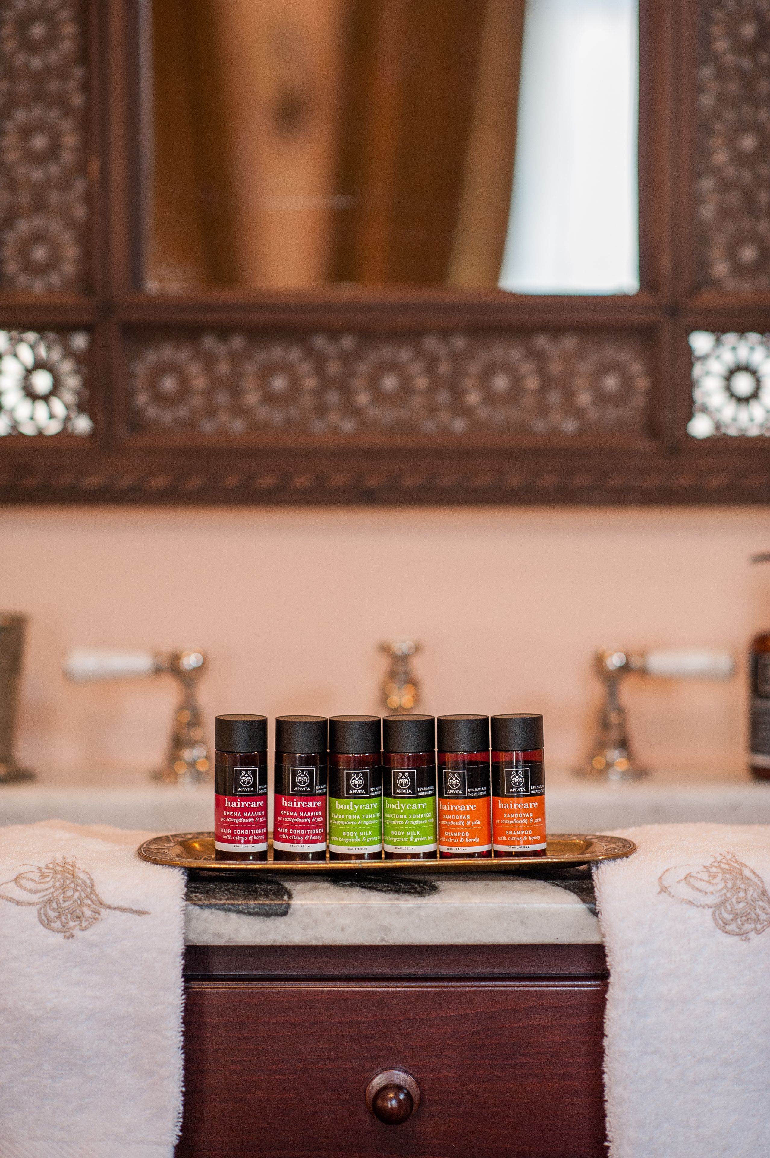 Un aparador de madera con espejo y una bandeja que contiene cinco productos para el cabello.