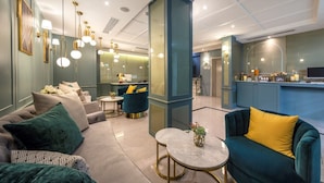 Een moderne hotel lobby met comfortabele zithoek, een bar en een grote spiegel.