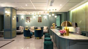 Een moderne hotellobby met een receptiebalie, een zithoek en decoratieve verlichting.