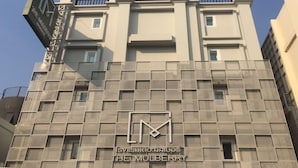 Een modern gebouw met een opvallend logo en de naam 'THE MULBERRY' op de gevel.