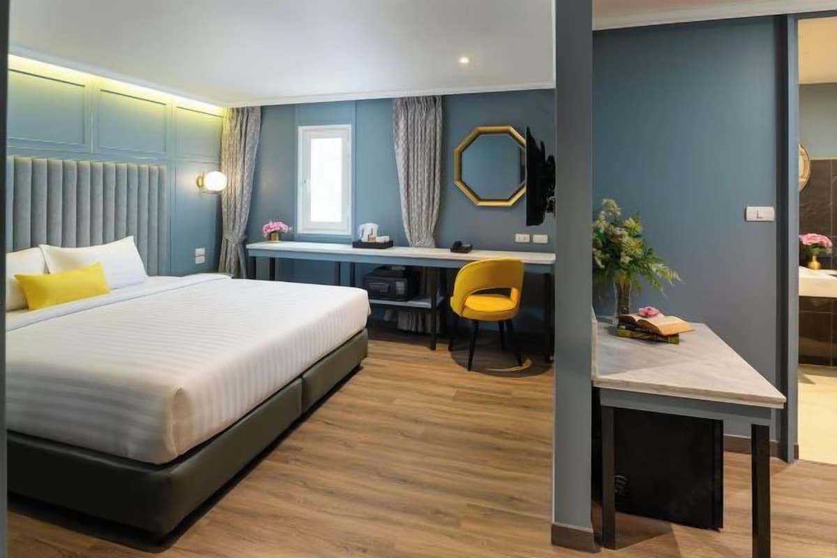 A modern hotel room with a large bed, a desk, and a chair.
