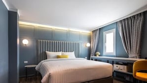 Een moderne slaapkamer met een bed, nachtkastjes, een bureau en een stoel.