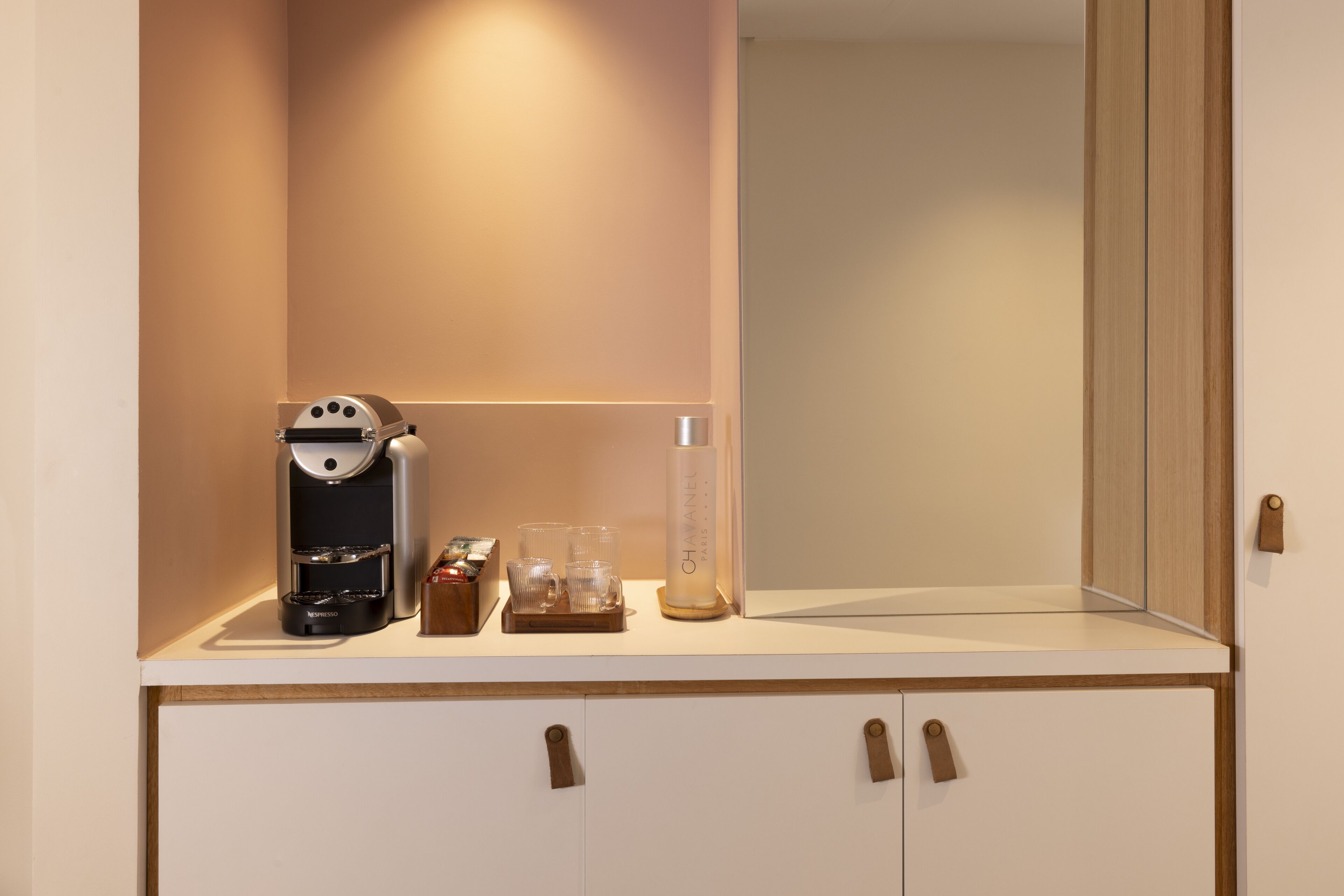A kitchenette with a coffee maker, a candle, and glassware on the countertop.