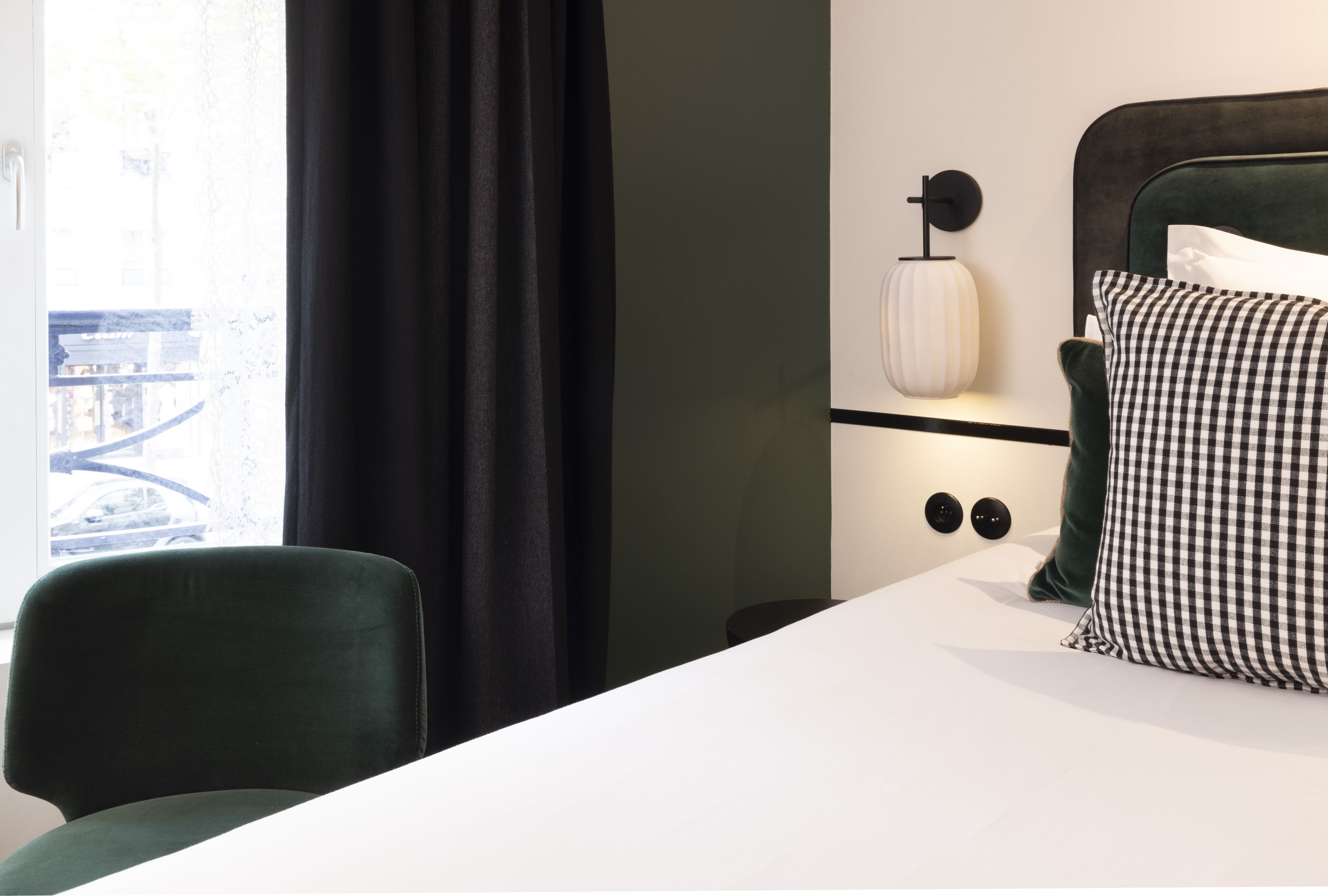 A hotel room with a bed, a chair, a nightstand, and a lamp.