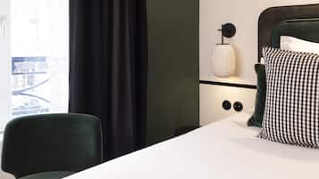 A hotel room with a bed, a chair, a nightstand, and a lamp.