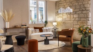 A modern living room with a sofa, armchairs, a coffee table, and a fireplace. - Hotel Chavanel Paris (Paris)