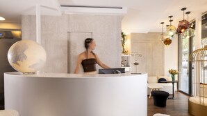 Et modtagelsesområde med et moderne design, der inkluderer en stor globus skulptur, et receptionsskrivebord og et siddeområde med hvidt og sort møbler.