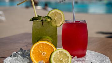 Two drinks on a table with ice and fruit slices.