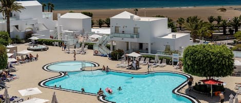 Una piscina al aire libre, sombrillas, tumbonas