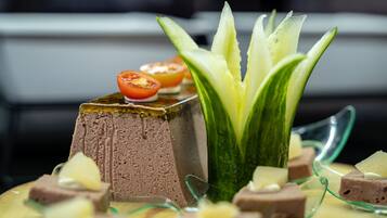 A dessert plate with a layered cake, a cucumber garnish, and small fruit pieces.