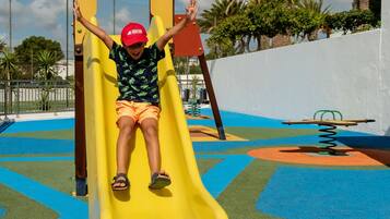 Kids can play on the playground's rubberized surface surrounded by palm trees.